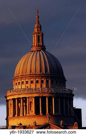 Stock Photo - The dome of St. Paul's Cathedral caught in a sudden burst of warm light breaking through dark clouds on a miserable Winter evening in London, England.. Fotosearch