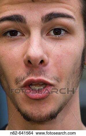 Picture - The face of a teenager who looks toward the camera making a funny face, mouth open. Fotosearch