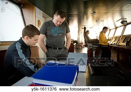 The first officer and cadet of container-vessel MV Flintercape are reading documentation about the ship on de ship's bridge, during a voyage from Rotterdam, Netherlands, to Sundsvall, Sweden. View Large Photo Image Stock Photograph - The first officer and cadet of container-vessel MV Flintercape are reading documentation about the ship on de ship's bridge, during a voyage from Rotterdam, Netherlands, to Sundsvall, Sweden.. Fotosearch