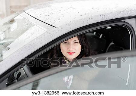 Stock Photograph - The girl in a fur coat sitting in the car. Fotosearch