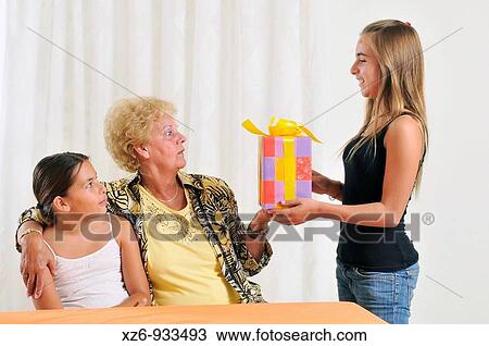 The girl passes the present to the grandma Sister hugging grandma View Large Photo Image Stock Image - The girl passes the present to the grandma Sister hugging grandma. Fotosearch