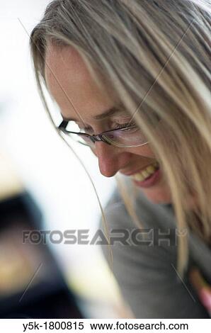 Stock Photography - The Hague, Netherlands. Portrait of a middle-aged blonde woman with glasses in her living room. An profile.. Fotosearch