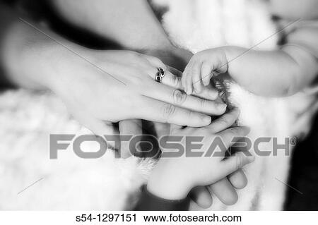 Stock Image - The hands of a mother, father, toddler, and newborn. Fotosearch