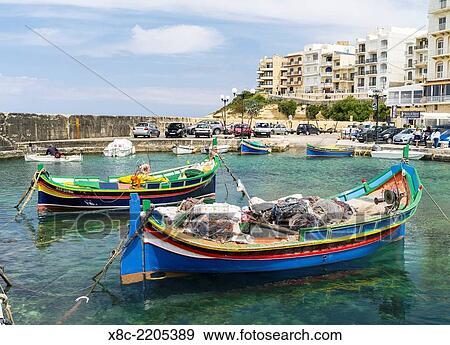 The island of Gozo in the maltese archipelago. The former fishing village Marsalforn with modern hotel buildings and traditional fishing boats called Luzzu in the harbour. Europe, Southern Europe, Malta, April. View Large Photo Image Stock Photo - The island of Gozo in the maltese archipelago. The former fishing village Marsalforn with modern hotel buildings and traditional fishing boats called Luzzu in the harbour. Europe, Southern Europe, Malta, April.. Fotosearch