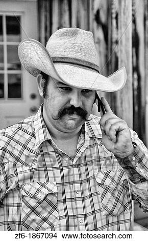 The life of a cowboy in the West USA as cowboy talks on modern cell phone to communicat View Large Photo Image Picture - The life of a cowboy in the West USA as cowboy talks on modern cell phone to communicat. Fotosearch