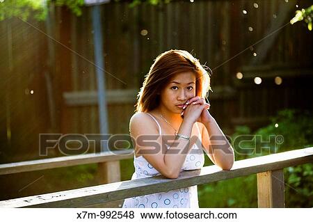 The rays of the setting sun lights the hair of a young Asian woman View Large Photo Image Stock Photo - The rays of the setting sun lights the hair of a young Asian woman. Fotosearch