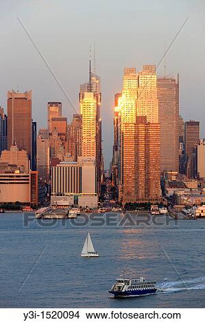 The setting sun reflects off the windows of Manhattan skyscrapers on 42nd street in New York City, New York, USA as viewed over the Hudson River from New Jersey View Large Photo Image Picture - The setting sun reflects off the windows of Manhattan skyscrapers on 42nd street in New York City, New York, USA as viewed over the Hudson River from New Jersey. Fotosearch