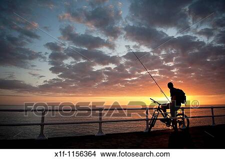 The silhouette of a young man on a bicycle at sunset, about to go fishing, cardigan bay west wales UK View Large Photo Image Picture - The silhouette of a young man on a bicycle at sunset, about to go fishing, cardigan bay west wales UK. Fotosearch