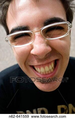 Stock Photo - The smiling face of a teenager with glasses that looks toward the camera. Fotosearch