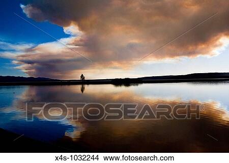 Picture - The sun reflects on Yellowstone Lake behind clouds of smoke from a forest fire. Fotosearch