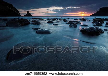 The sun sets over the dark boulders at Talisker Bay in the Highlands of Scotland. View Large Photo Image Stock Image - The sun sets over the dark boulders at Talisker Bay in the Highlands of Scotland.. Fotosearch