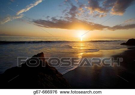 The sunset sets as clouds relect in the surf on a beach In Malibu, California, USA. View Large Photo Image Stock Photograph - The sunset sets as clouds relect in the surf on a beach In Malibu, California, USA.. Fotosearch