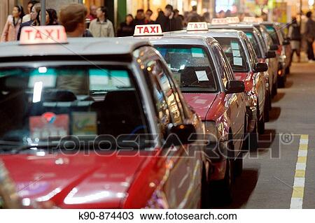 Stock Image - The typical red taxis queueing up idle at a taxi stand in Wanchai (Wan Chai) and waiting for customer, Hong Kong Island, Hong Kong, China, Southeast Asia. Fotosearch