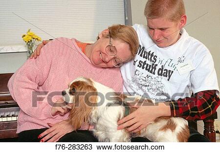 Stock Image - Therapy dog working with special needs, a student and a woman who has had a stroke. Fotosearch