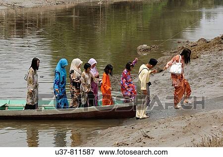 These Malays wearing new costumes go visiting during Selamat Aidil Filtri (New Year). They have to cross this small river by using sampan (boat) and heading for the city centre. View Large Photo Image Stock Photo - These Malays wearing new costumes go visiting during Selamat Aidil Filtri (New Year). They have to cross this small river by using sampan (boat) and heading for the city centre.. Fotosearch
