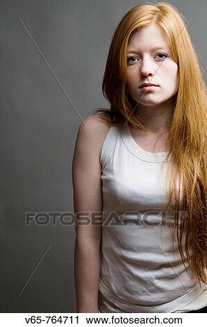 Stock Image - thin slim slender size zero Red haired teenage girl looking moody, wearing white vest. Fotosearch