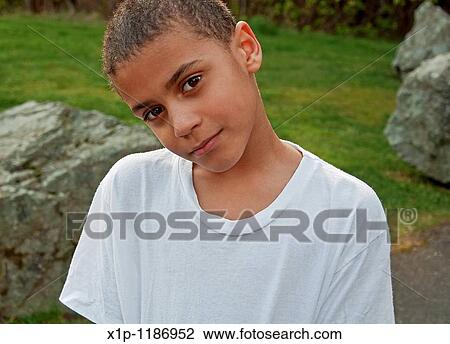 This closeup portrait is a cute 8 year old bi-racial boy wearing plain white T-shirt and outside with grass and some large rocks in the background Background is intentionally blurred to emphasize subject. View Large Photo Image Stock Image - This closeup portrait is a cute 8 year old bi-racial boy wearing plain white T-shirt and outside with grass and some large rocks in the background Background is intentionally blurred to emphasize subject.. Fotosearch