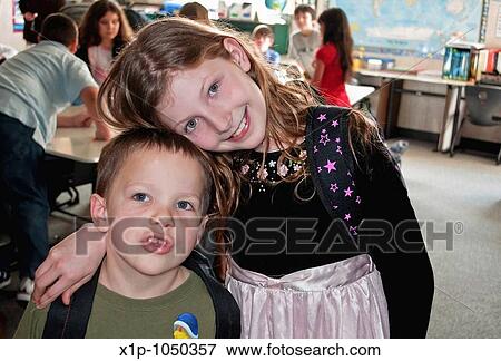 This cute third grade girl hugs her kindergarten aged brother in a classroom with other students blurred in the background View Large Photo Image Stock Photo - This cute third grade girl hugs her kindergarten aged brother in a classroom with other students blurred in the background. Fotosearch