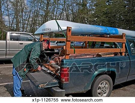 This middle aged Caucasian man is preparing the back of his truck with camping gear with a kayak loaded on top in readiness for a camping trip View Large Photo Image Stock Photography - This middle aged Caucasian man is preparing the back of his truck with camping gear with a kayak loaded on top in readiness for a camping trip. Fotosearch