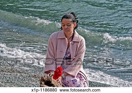 This pretty multi racial woman in her thirties is wearing a pink coat and holding red carnation flowers at the beach Her mood is one of quiet reflection and introspection View Large Photo Image Stock Image - This pretty multi racial woman in her thirties is wearing a pink coat and holding red carnation flowers at the beach Her mood is one of quiet reflection and introspection. Fotosearch