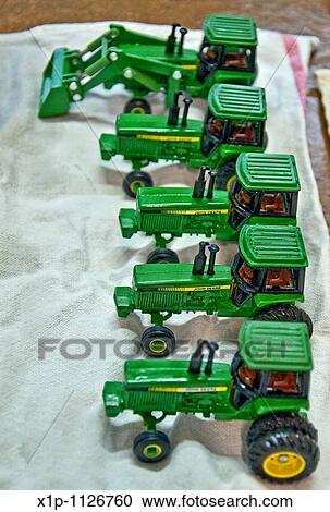 This vertical image shows a row of 5 green John Deere vintage toy tractors being prepped for an antique show, freshly washed and drying on a towel Focus is intentionally set on the 2nd tractor to pull the eyes into the photo View Large Photo Image Stock Image - This vertical image shows a row of 5 green John Deere vintage toy tractors being prepped for an antique show, freshly washed and drying on a towel Focus is intentionally set on the 2nd tractor to pull the eyes into the photo. Fotosearch
