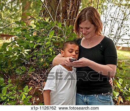 This young modern Caucasian mother is text messaging with her cute bi-racial son in a family moment together of learning technology Background is intentionally blurred to emphasize subject View Large Photo Image Stock Image - This young modern Caucasian mother is text messaging with her cute bi-racial son in a family moment together of learning technology Background is intentionally blurred to emphasize subject. Fotosearch