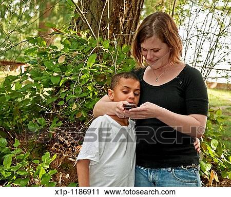 This young modern Caucasian mother is text messaging with her cute bi-racial son in a family moment together of learning technology Background is intentionally blurred to emphasize subject View Large Photo Image Stock Image - This young modern Caucasian mother is text messaging with her cute bi-racial son in a family moment together of learning technology Background is intentionally blurred to emphasize subject. Fotosearch