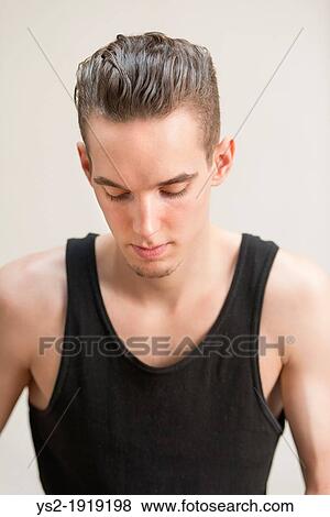 Thoughtful young adult man looking down with pensive expression View Large Photo Image Stock Photo - Thoughtful young adult man looking down with pensive expression. Fotosearch