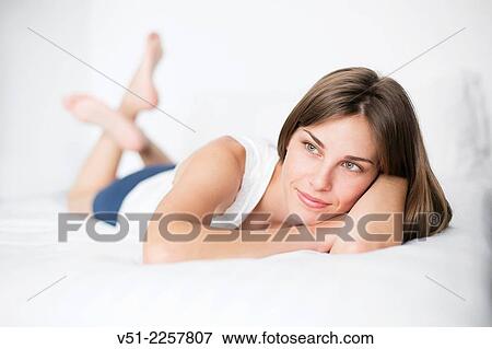 Stock Photo - Thoughtful young woman lying in bed. Fotosearch