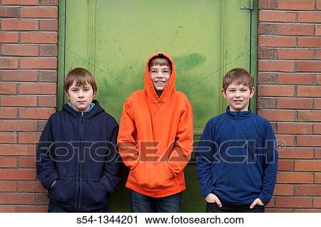 Three boys outdoors, standing against a building View Large Photo Image Stock Image - Three boys outdoors, standing against a building. Fotosearch