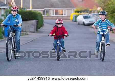 Three boys riding their bikes in a uk street View Large Photo Image Stock Photography - Three boys riding their bikes in a uk street. Fotosearch