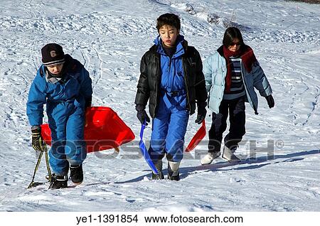 Three children carrying sleds up a snowy hill View Large Photo Image Picture - Three children carrying sleds up a snowy hill. Fotosearch