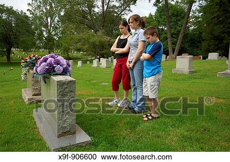 Three children mourn the loss of a family member The young ones gaze sadly at the headstone of the one they love View Large Photo Image Stock Image - Three children mourn the loss of a family member The young ones gaze sadly at the headstone of the one they love. Fotosearch
