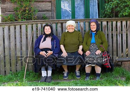Stock Image - Three elderly ladies on a bench, Botiza, Maramures, Romania. Fotosearch