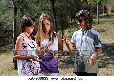 Stock Image - three friends at the park counting on his fingers. Fotosearch