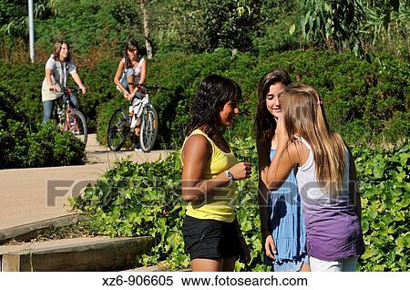 three friends telling secrets in the foreground, while two more arrive on a bicycle View Large Photo Image Stock Photography - three friends telling secrets in the foreground, while two more arrive on a bicycle. Fotosearch