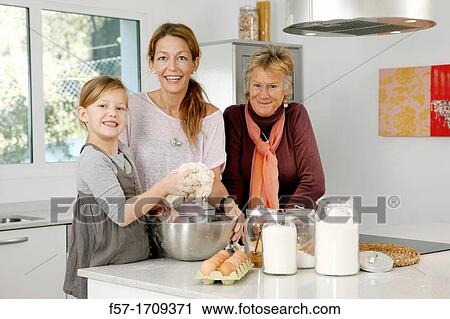 Stock Image - Three generations of women in the kitchen. Fotosearch