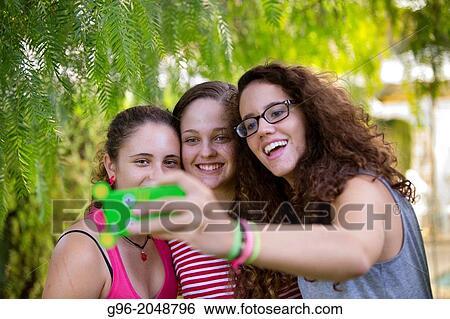 three girl selfportraiting with a phone. View Large Photo Image Stock Photograph - three girl selfportraiting with a phone.. Fotosearch