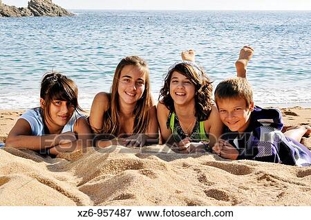 Three girls and a teenage boy, lying on the beach and smiling View Large Photo Image Stock Photo - Three girls and a teenage boy, lying on the beach and smiling. Fotosearch