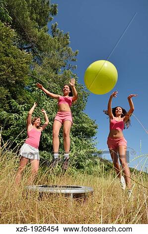 Picture - Three girls exercising with fitness ball at field. Fotosearch
