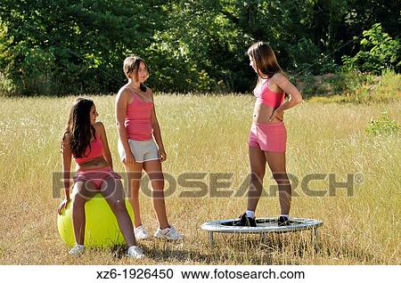 Stock Image - Three girls exercising with fitness ball at field. Fotosearch