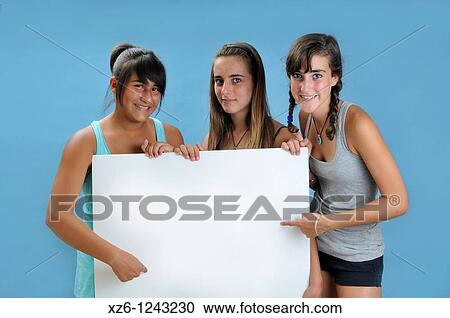 Stock Image - Three girls holding a blank sign, with blue backgroud. Fotosearch