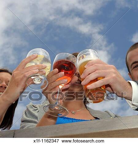 Three guests clinking their drinks glasses together at a wedding reception, UK View Large Photo Image Stock Photo - Three guests clinking their drinks glasses together at a wedding reception, UK. Fotosearch