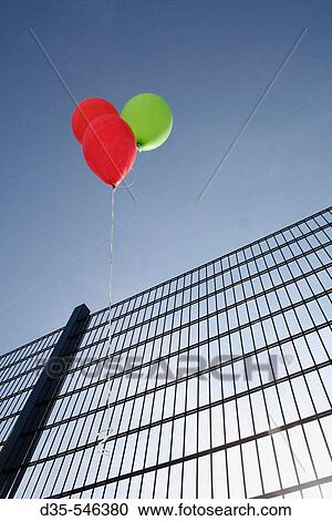 Stock Image - Three helium balloons hanging on fence. Fotosearch