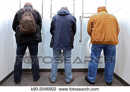 Stock Image - Three men seen from backside, standing in the toilet, London, England, Great Britain, United Kingdom, Europe.. Fotosearch