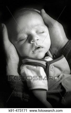Stock Image - Three month old baby being held in fathers hands. Fotosearch