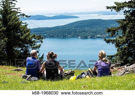 Three people enjoy the view from Mount Warburton Pike, a mountain on Saturna Island in the Gulf Islands of British Columbia, Canada. View Large Photo Image Stock Image - Three people enjoy the view from Mount Warburton Pike, a mountain on Saturna Island in the Gulf Islands of British Columbia, Canada.. Fotosearch