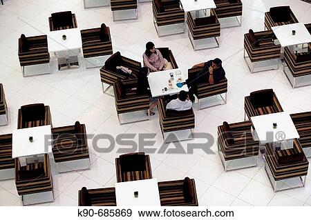 Stock Photo - Three people sitting and talking in the fancy? La Moda? cafe in the luxurios shopping mall Plaza Indonesia of Jakarta, Indonesia, Southeast Asia. Fotosearch