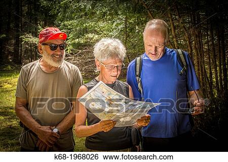 Stock Photograph - Three senior hikers look at a map in a forest on Saturna Island, Gulf Islands, BC, Canada. Fotosearch