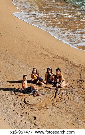 Three teenage girls on the beach drawing a heart in the sand around a boy View Large Photo Image Stock Photo - Three teenage girls on the beach drawing a heart in the sand around a boy. Fotosearch